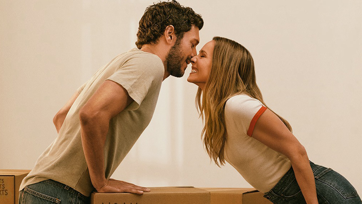 Joanne et Noah, les héros de Nobody Wants This, se penchent pour s'embrasser au-dessus de cartons de déménagement (visuel officiel de la saison 3 sur Netflix)