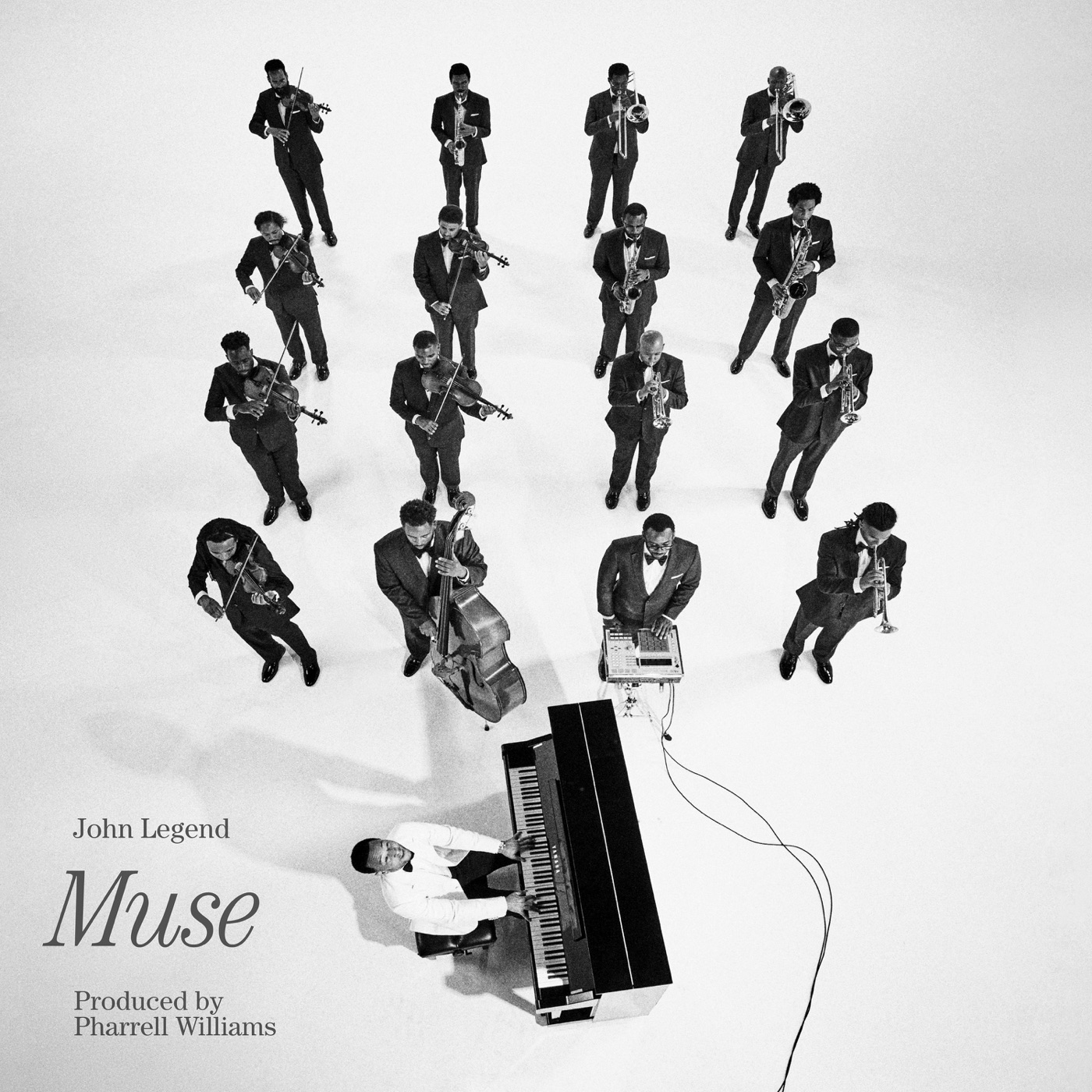 Pochette de l'album Muse de John Legend, vue en plongee d'un orchestre en smoking et de John Legend au piano en costume blanc