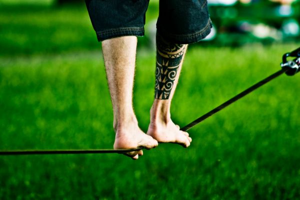 Pieds nus en équilibre sur une slackline tendue au-dessus de l'herbe dans un parc