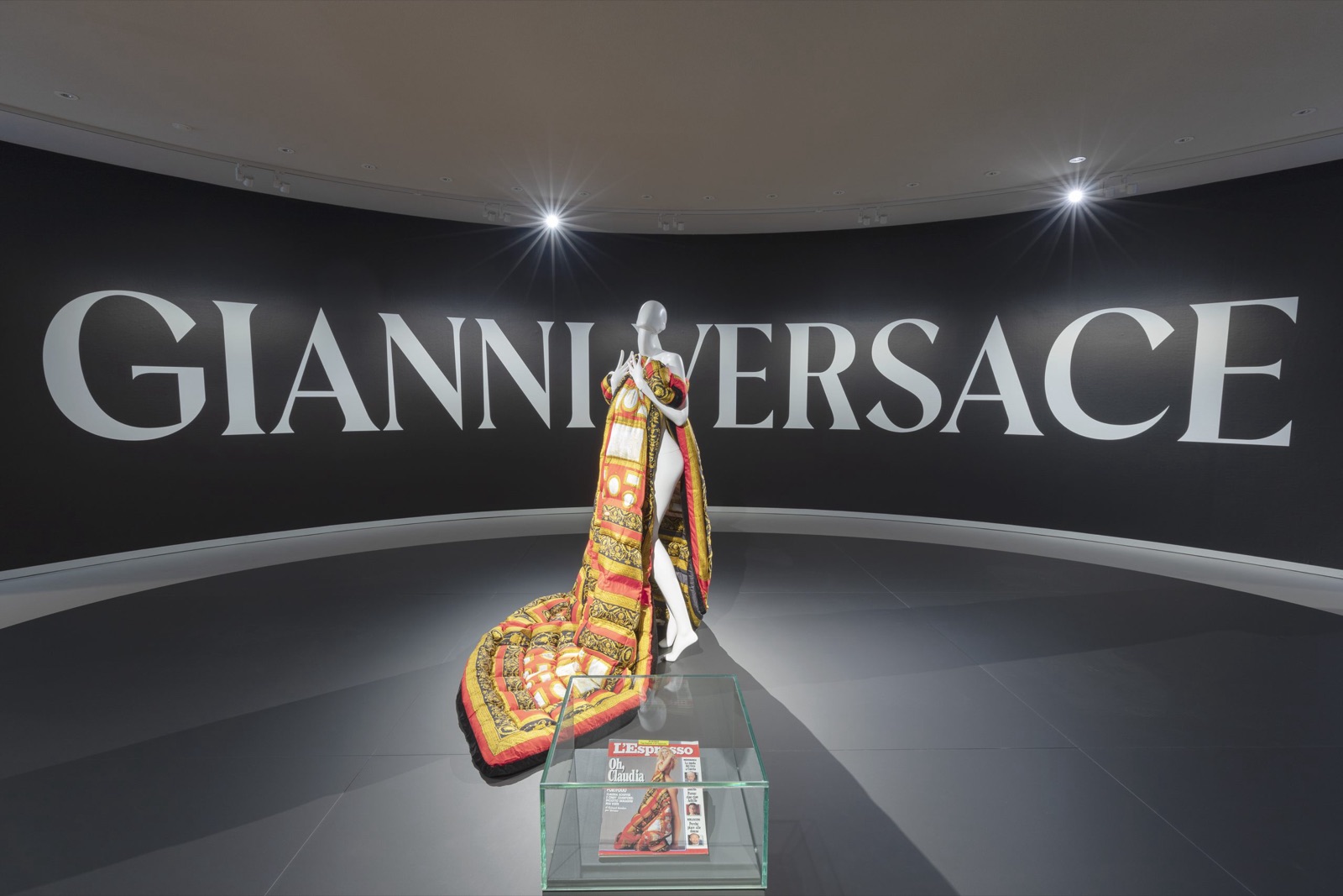 Une silhouette Versace aux imprimés baroques dorés devant le mur GIANNI VERSACE, à l'exposition du musée Maillol