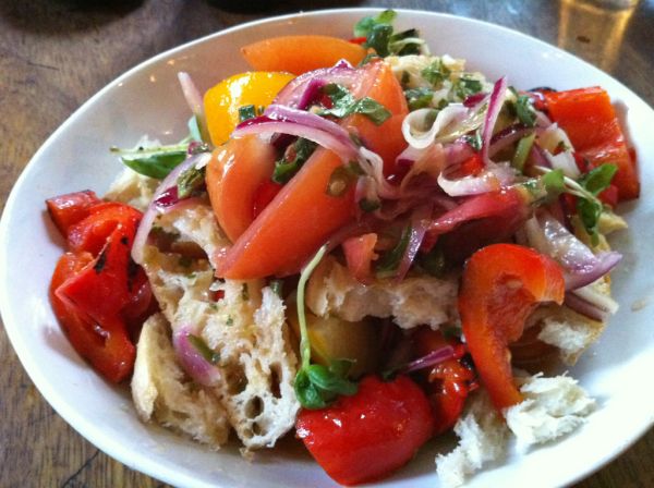 Salade panzanella toscane: tomates, pain rassis, oignon rouge et basilic dans une assiette blanche