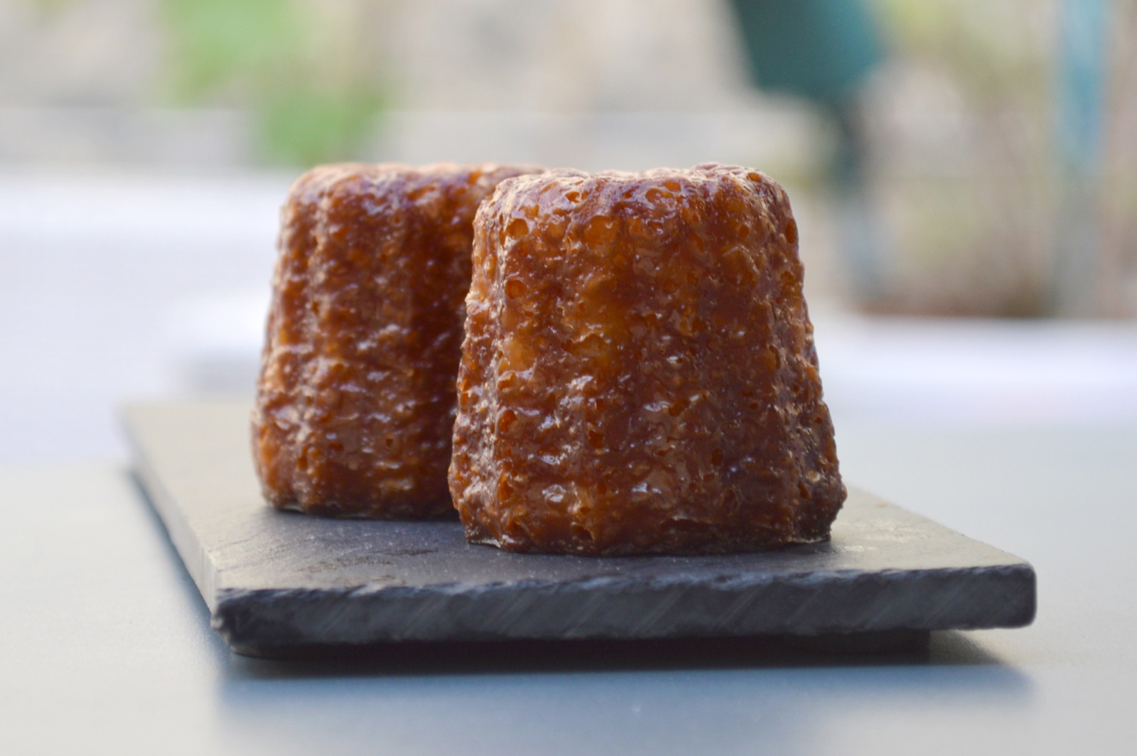Deux canelés bordelais à la coque caramélisée posés sur une ardoise