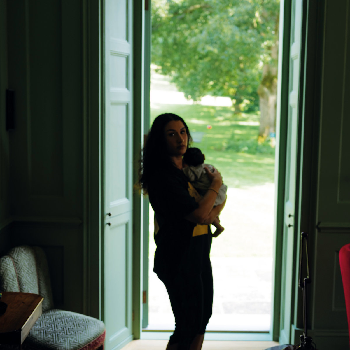 Pochette de l'album Gentlewoman de Cleo Sol : la chanteuse tient son enfant dans les bras devant une porte-fenêtre ouverte sur un jardin