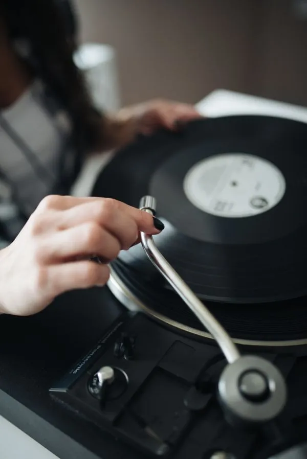 Une personne pose un disque sur une platine vinyle dans un salon cosy