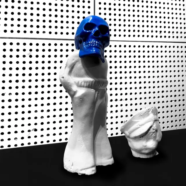 Pochette de l'album Frozen Charlotte de Jack White : une sculpture de poupée blanche surmontée d'un crâne bleu, sur fond perforé noir et blanc