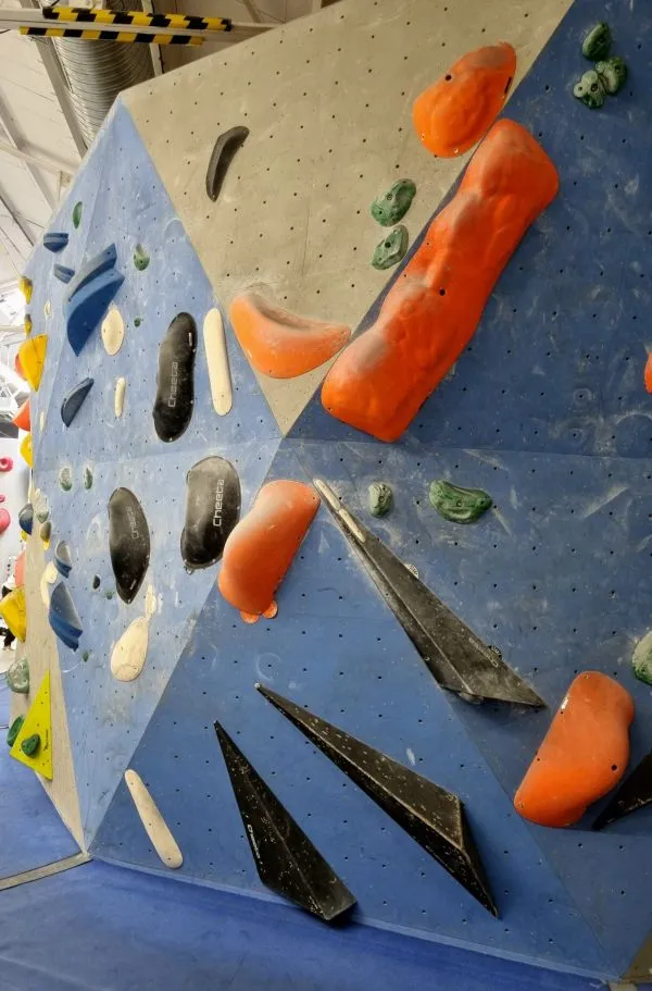Mur d'escalade de bloc en salle avec de nombreuses prises en plastique colorees